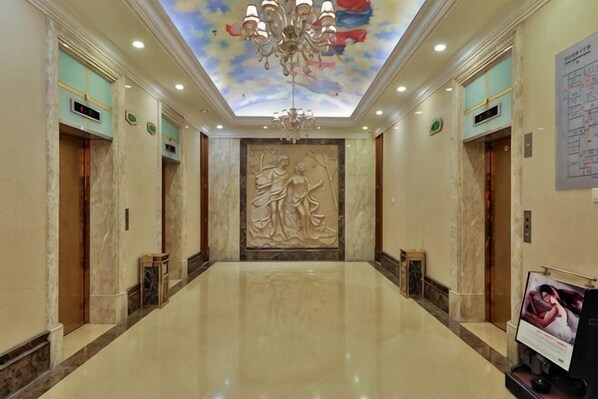 A hotel lobby with a marble floor, a chandelier, a ceiling mural, and a large wall sculpture. - Vienna International Hotel (Beijing Niujie Guang'anmennei Subway Station Branch) (Beijing)