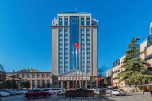 A tall hotel with a central entrance, multiple floors, and a flag on top. - Vienna International Hotel (Beijing Niujie Guang'anmennei Subway Station Branch) (Beijing)