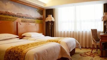 A hotel room with two beds, a painting on the wall, a desk, and a chair.