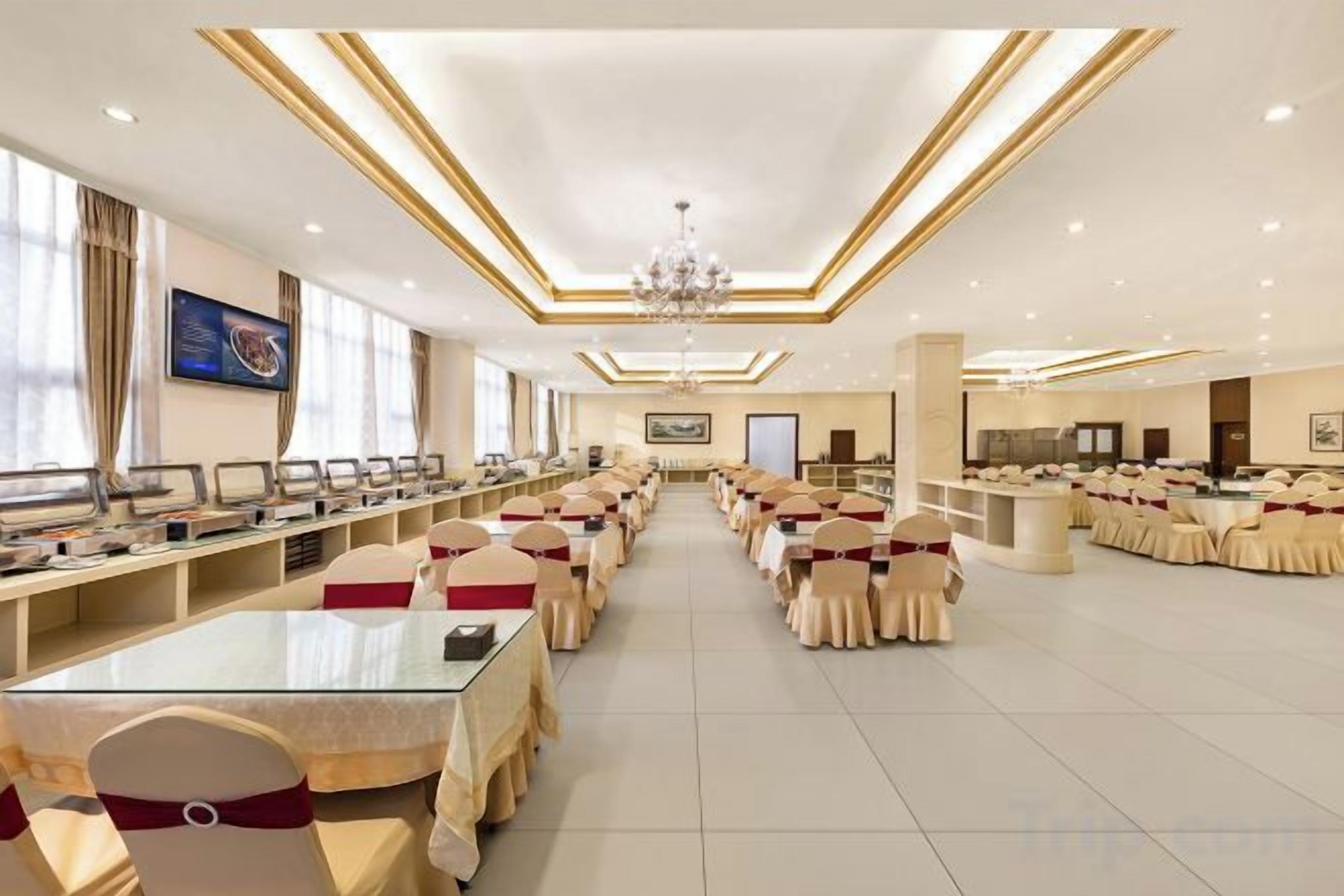 A banquet hall with long tables, chairs, and a chandelier.