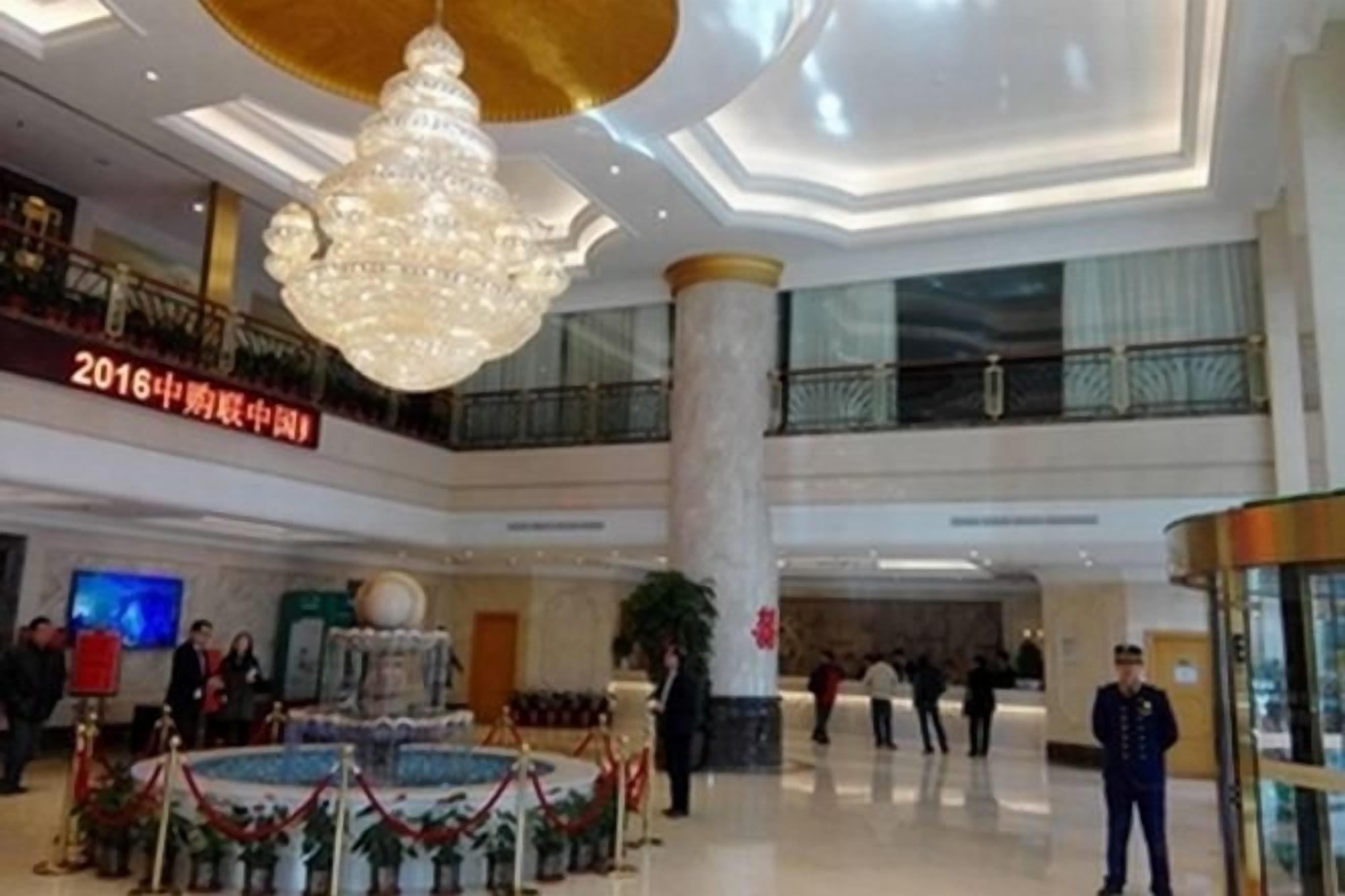 A spacious lobby with a grand chandelier, multiple levels, and a large column.