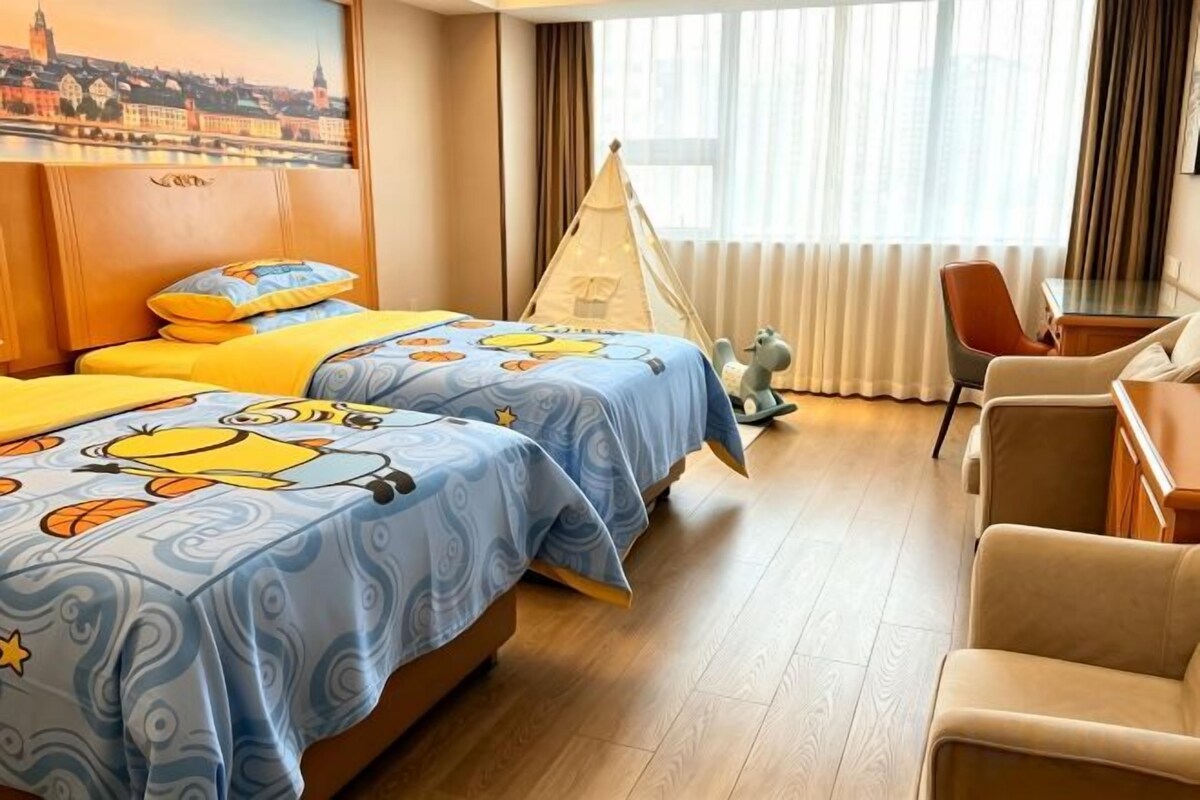 A hotel room with two beds, a desk, a chair, and a window with curtains.