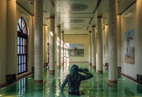Una gran piscina interior con columnas, un mural y una estatua.. Palazzo Manzi Terme & Spa