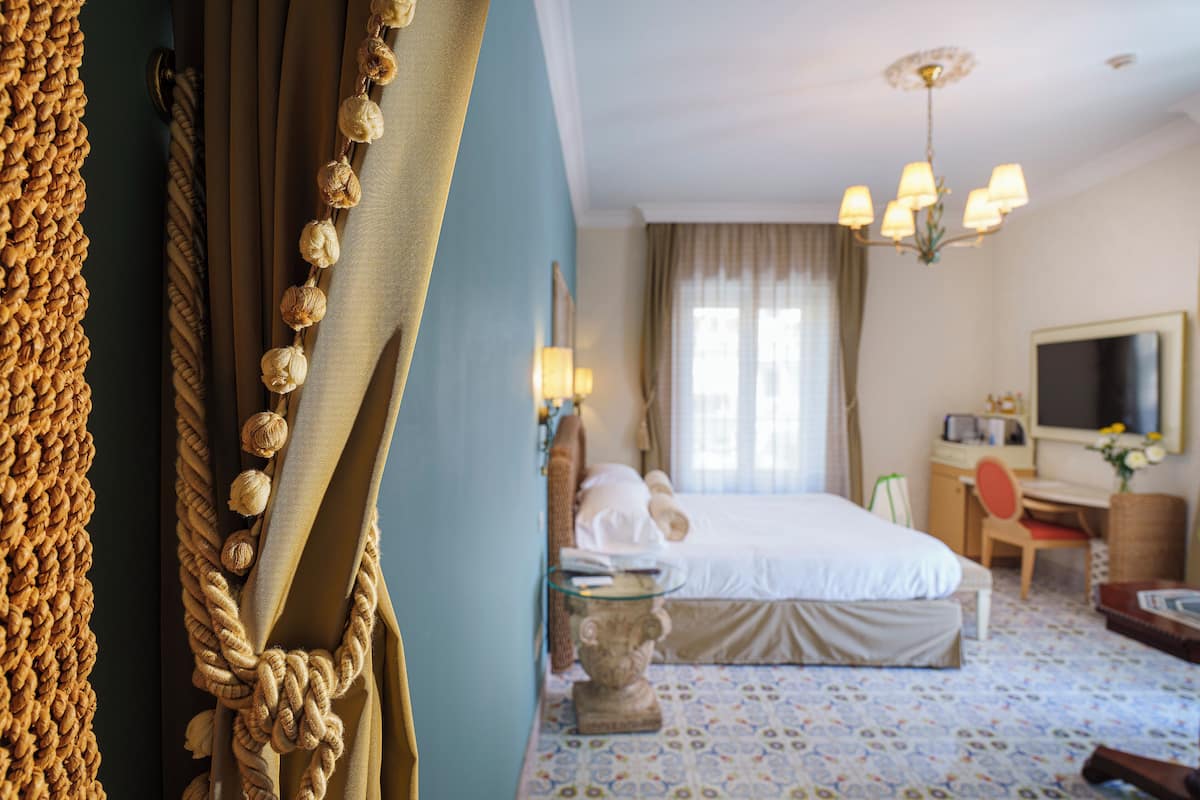 Een hotelkamer met een bed, een bureau, een stoel, een televisie en een raam met gordijnen.