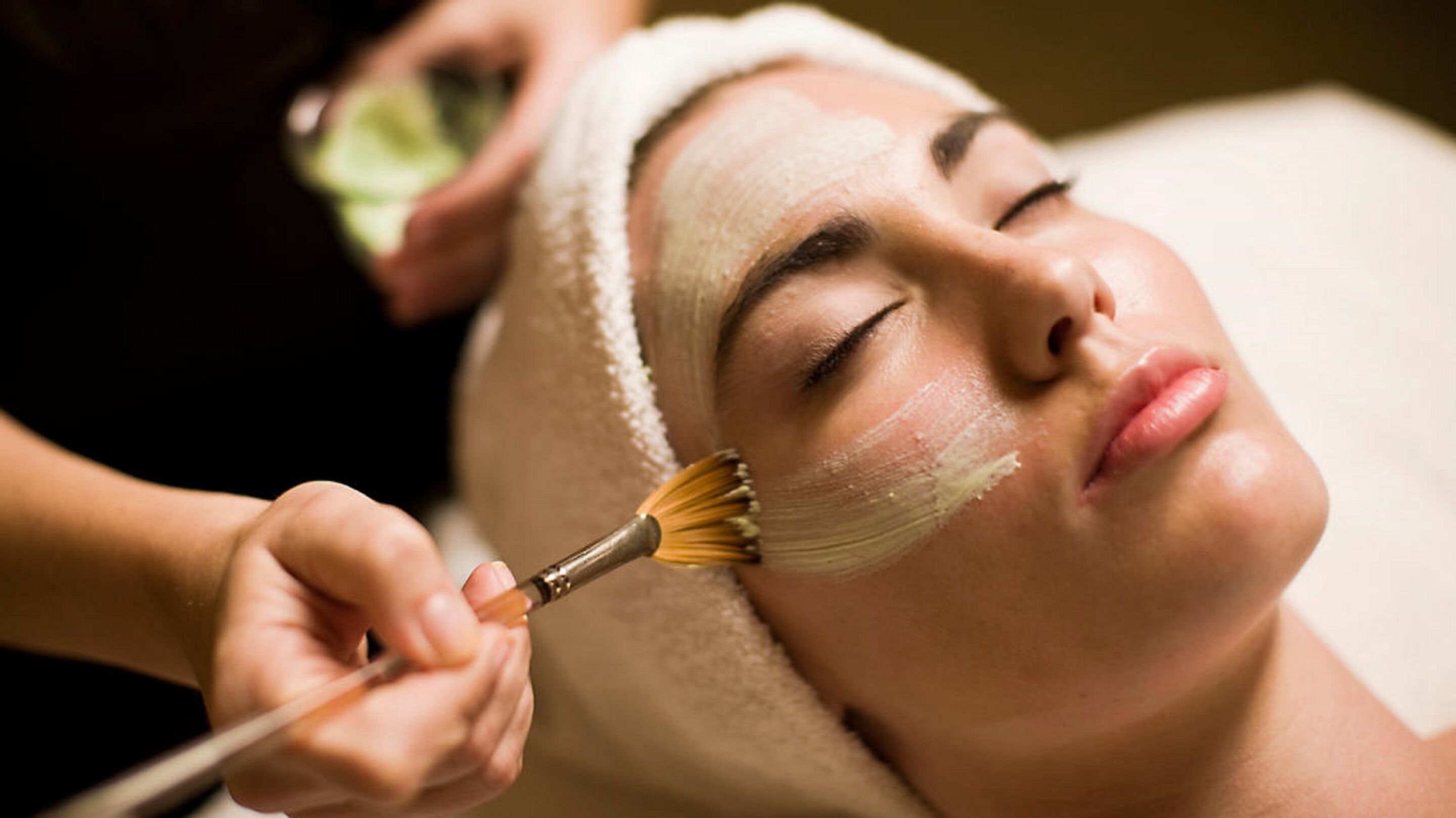 A person receiving a facial treatment with a brush.