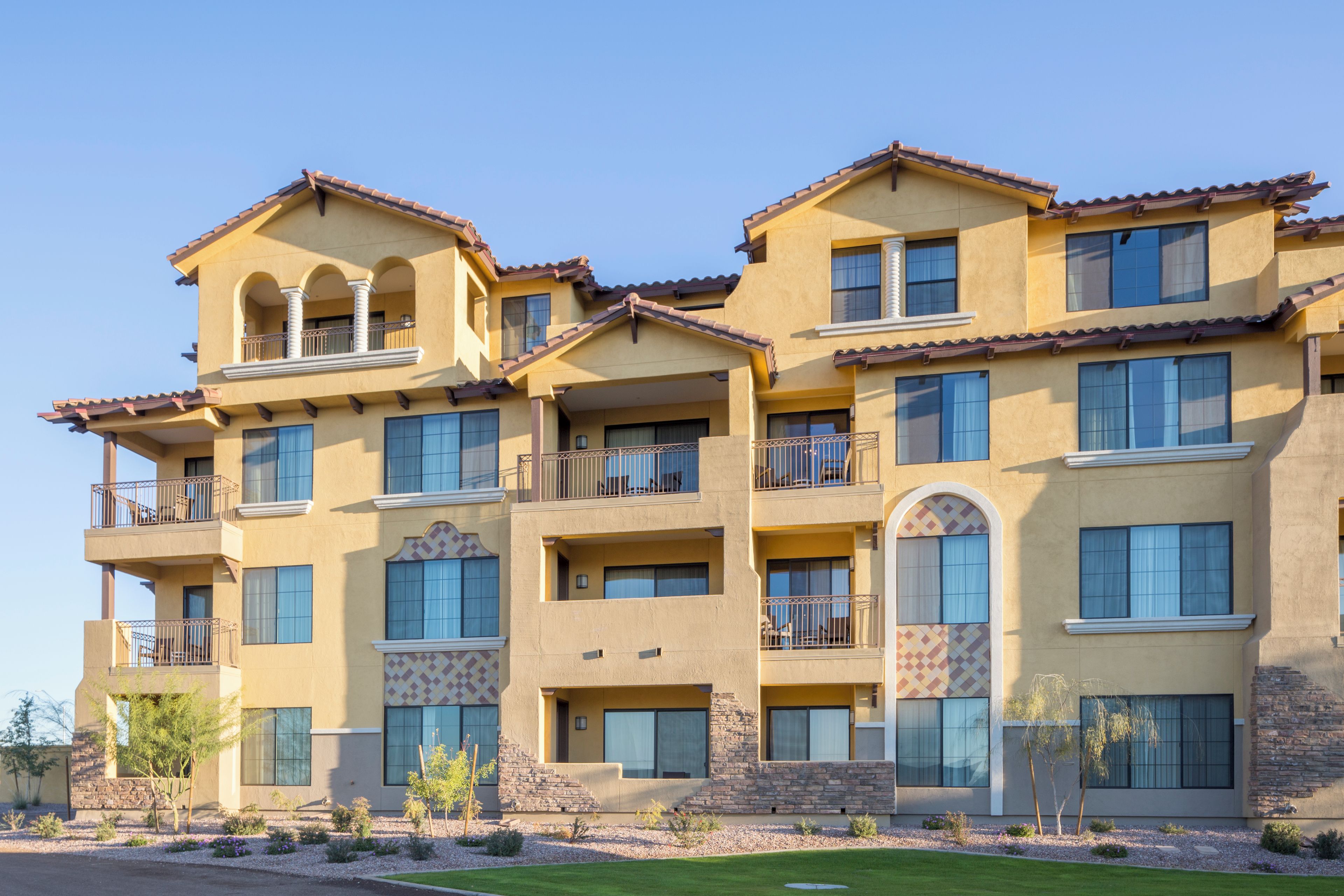 A multi-story residential building with balconies, large windows, and a stone facade.