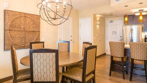 A dining area with a round table and six chairs, a chandelier, and a large decorative wall piece. - Bluegreen Vacations Cibola Vista Resort and Spa, an Ascend Collection Resort (Peoria)