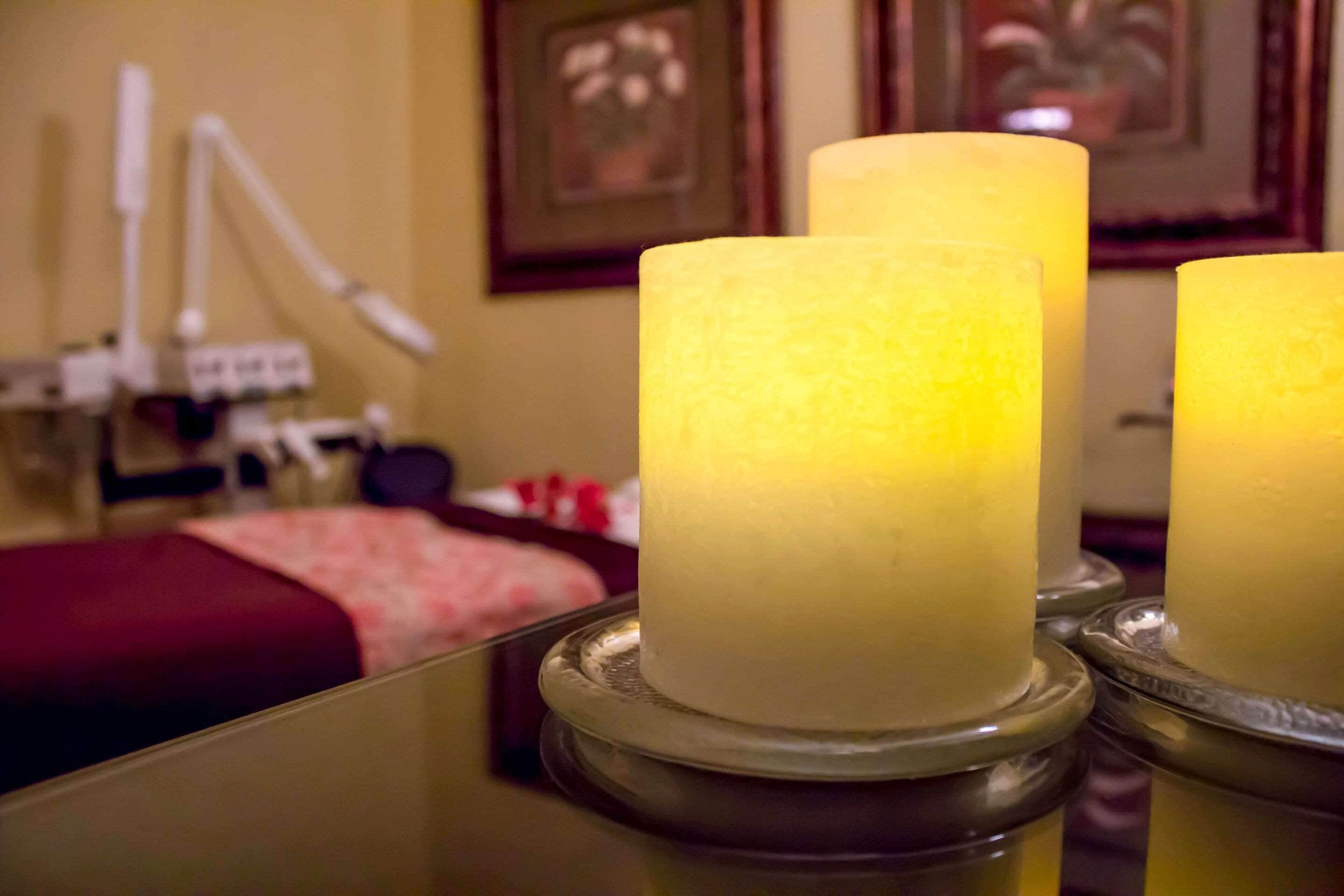 A room with a bed, a mirror, and two candles on a table.