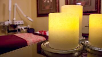 A room with a bed, a mirror, and two candles on a table.