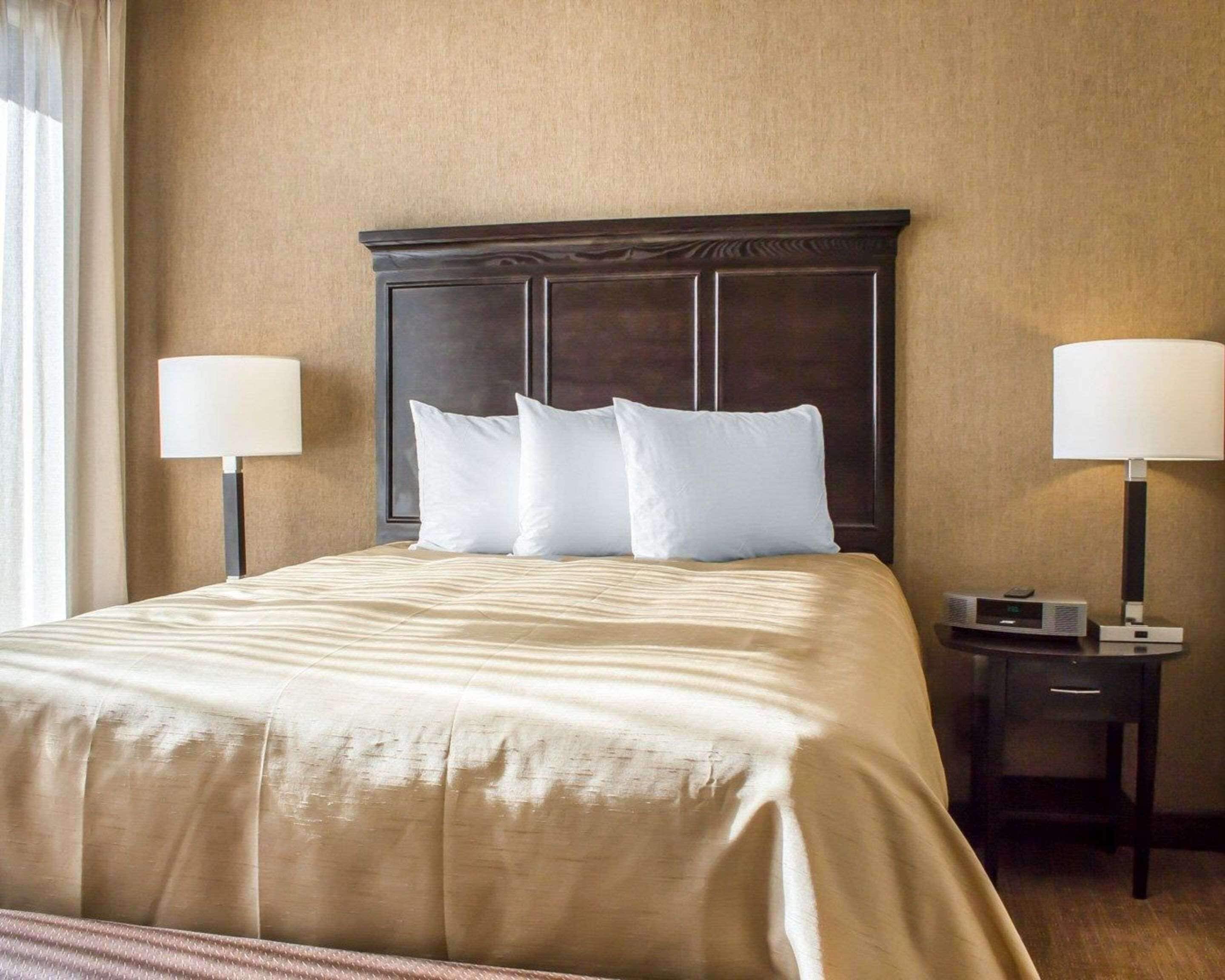 Een hotelkamer met een groot bed, twee nachtkastjes met lampen en een aan de muur bevestigde televisie.