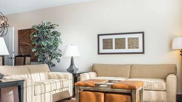A living room with two sofas, a coffee table, a side table with a lamp, a potted plant, and framed artwork on the wall.