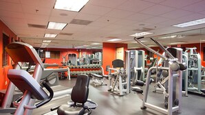 Ein Fitnessstudio mit Laufbändern, Kraftgeräten und Kurzhanteln.