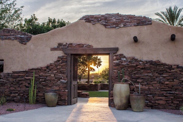 Un edificio con fachada de piedra, puerta de madera y grandes macetas.