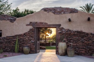 Un edificio con fachada de piedra, puerta de madera y grandes macetas.