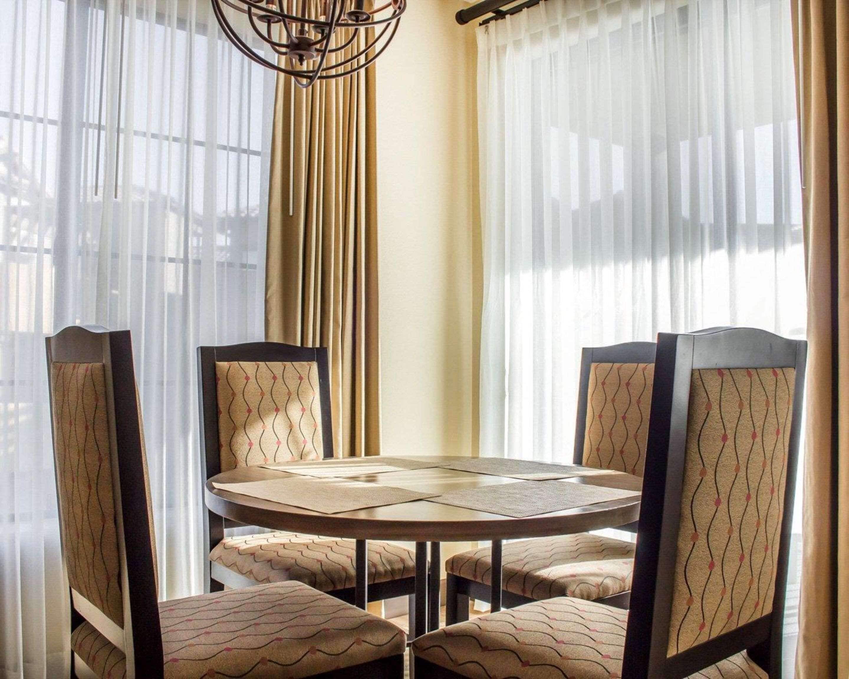 A dining area with a round table and four chairs, each with a patterned cushion.