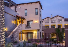 A multi-story residential building with a stone facade, multiple balconies, and a gated entrance.