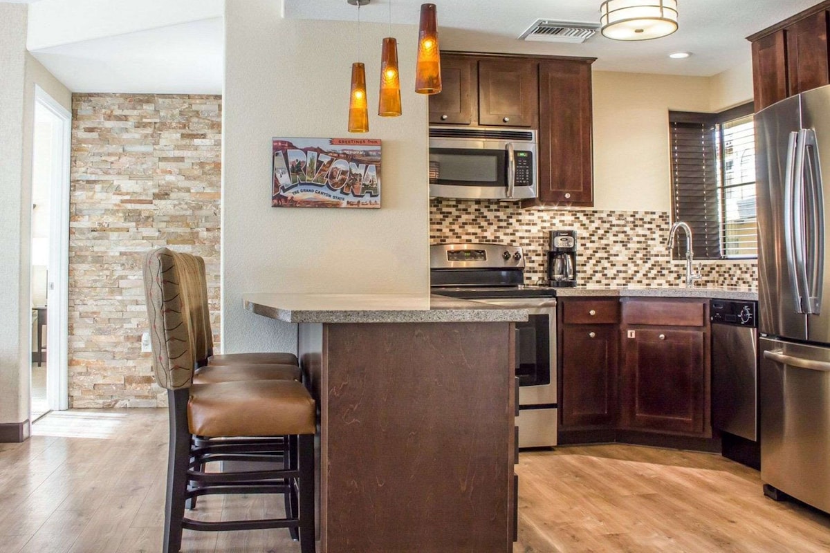 A modern kitchen with a central island, stainless steel appliances, and a stone backsplash.