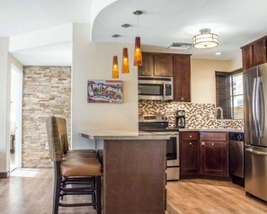 A modern kitchen with a central island, stainless steel appliances, and a stone backsplash. - Bluegreen Vacations Cibola Vista Resort and Spa, an Ascend Collection Resort (Peoria)