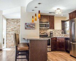 Una cocina moderna con una isla central, electrodomésticos de acero inoxidable y un salpicadero de piedra.
