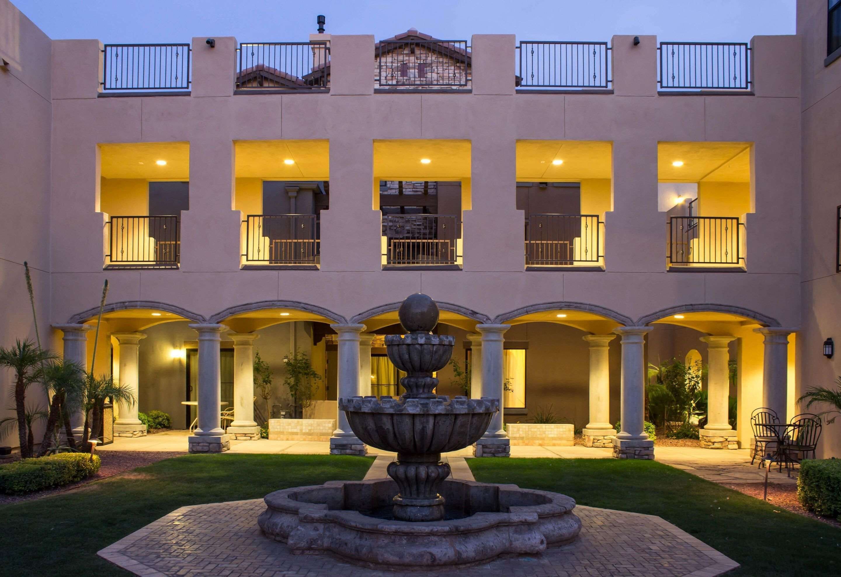 A multi-story building with a central courtyard featuring a fountain, columns, and outdoor seating.