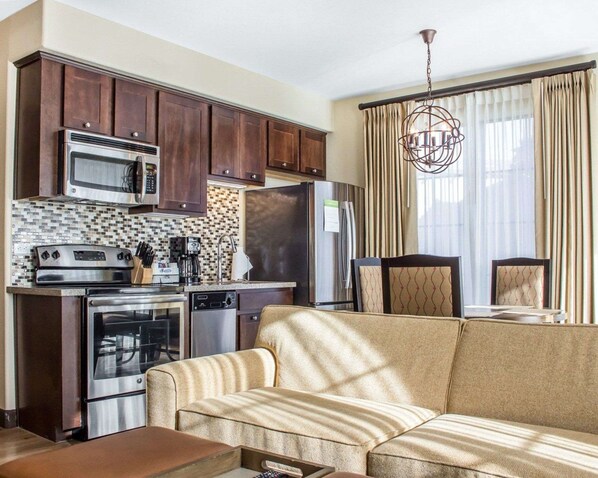 A compact living space with a kitchenette, including a microwave, stove, and refrigerator. There is a sofa and a dining area with chairs. - Bluegreen Vacations Cibola Vista Resort and Spa, an Ascend Collection Resort (Peoria)