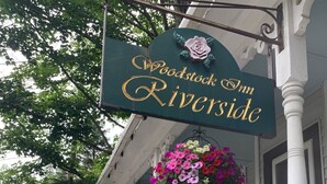 Señal del Woodstock Inn Riverside con un arreglo floral en el porche.