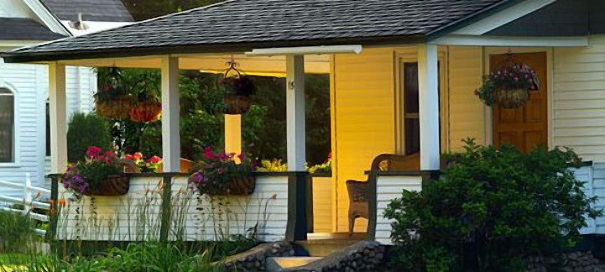 A house with a porch, a chair, and hanging flower baskets.