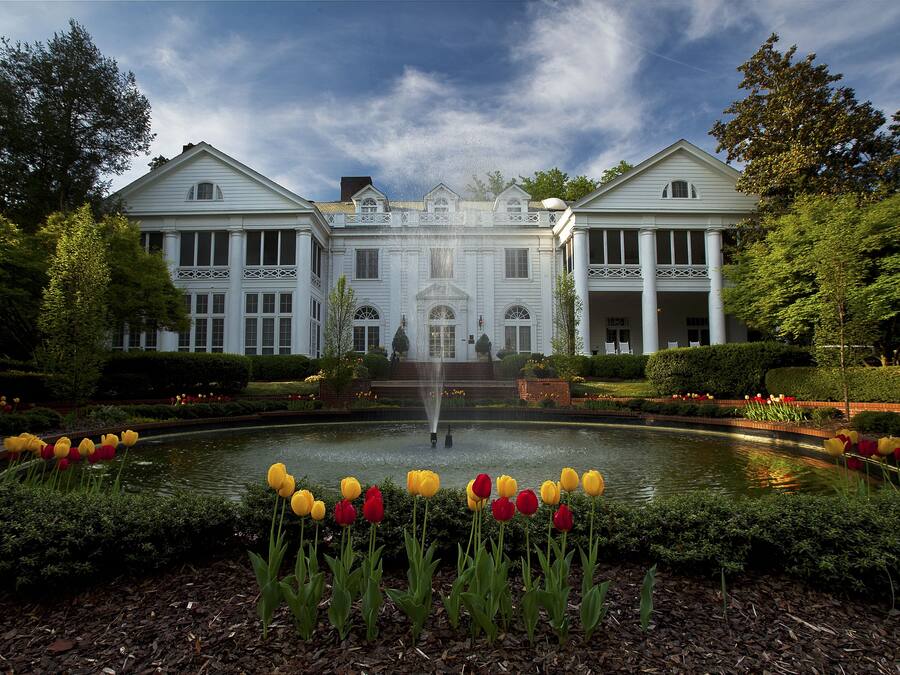 A large, symmetrical building with a central fountain, surrounded by well-maintained gardens and a variety of tulips.