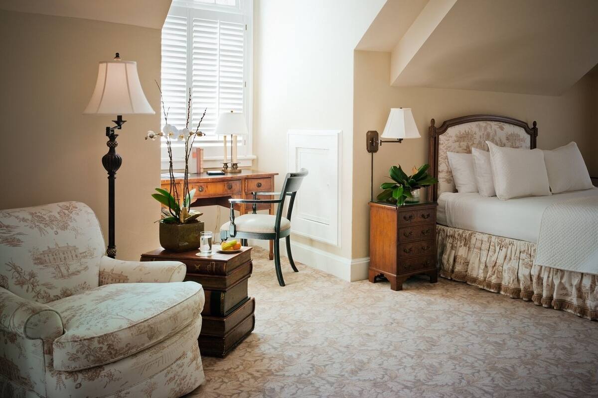 A cozy bedroom with a bed, a chair, a desk, and a lamp.