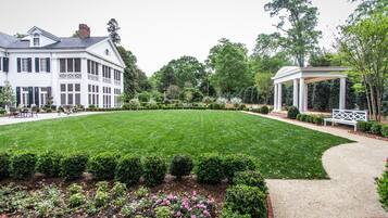 A large, white, two-story house with a well-maintained lawn and garden.