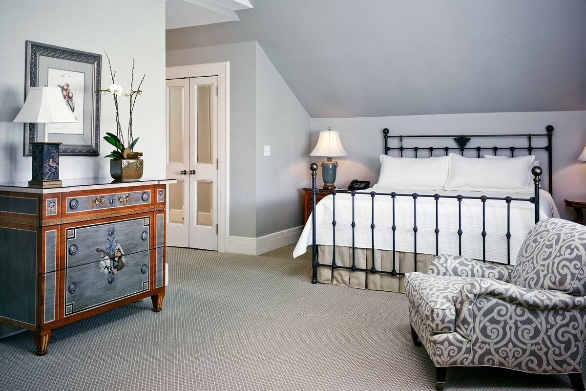 A bedroom with a bed, a dresser, a chair, and a nightstand.