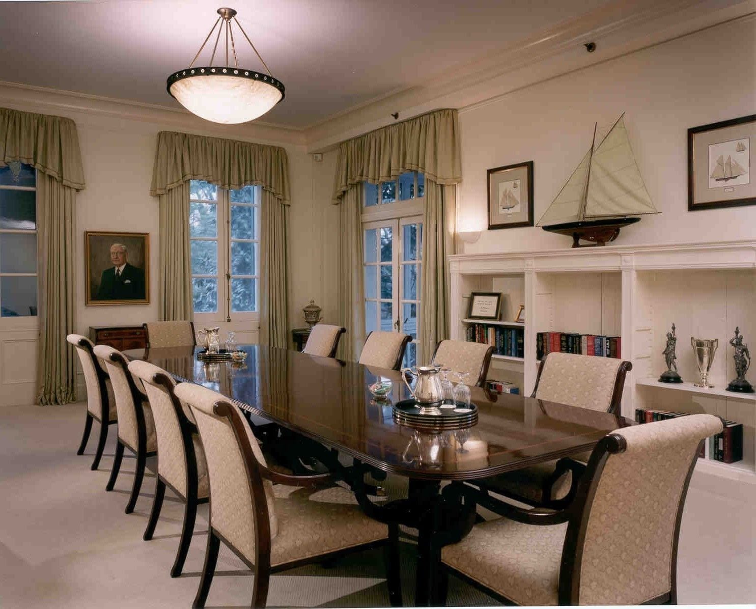 A formal dining room with a long table, chairs, and a chandelier.