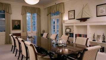 A formal dining room with a long table, chairs, and a chandelier.
