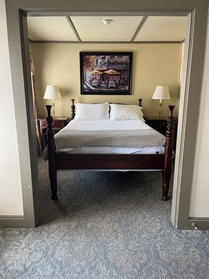 A neatly made bed with a white comforter and pillows, flanked by two bedside tables with lamps, in a room with a carpeted floor and a painting on the wall. - The Inn at Montpelier (Montpelier)