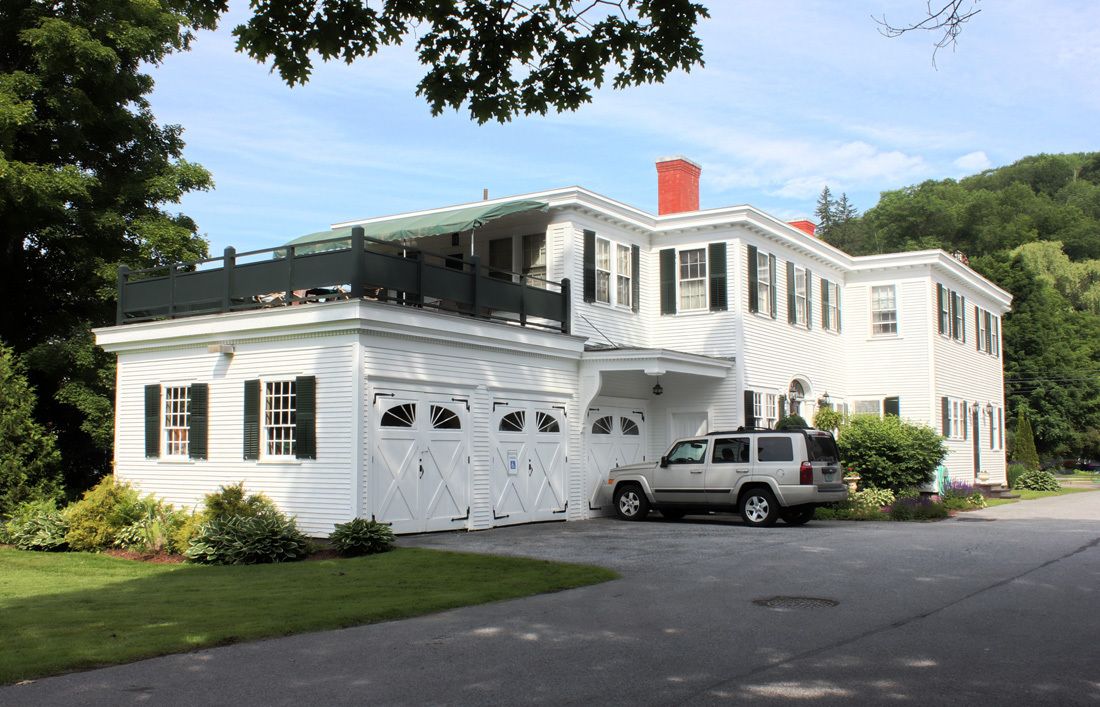Une grande maison blanche avec un porche abrité et un garage.