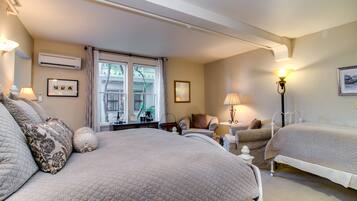 Une chambre d’hôtel avec deux lits, une fenêtre donnant sur un paysage agréable, une chaise, une lampe et un tableau au mur.