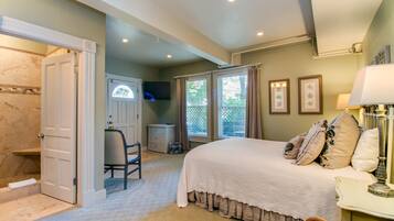 A bedroom with a large bed, a chair, a desk, and a window with curtains.