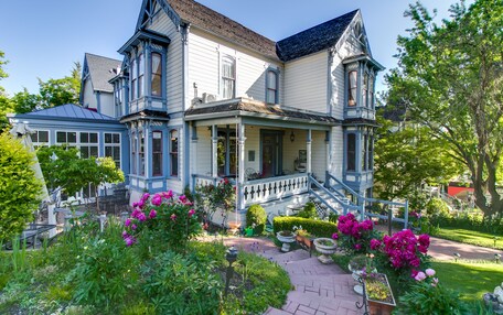 A large, two-story house with a wrap-around porch and a steeply pitched roof.