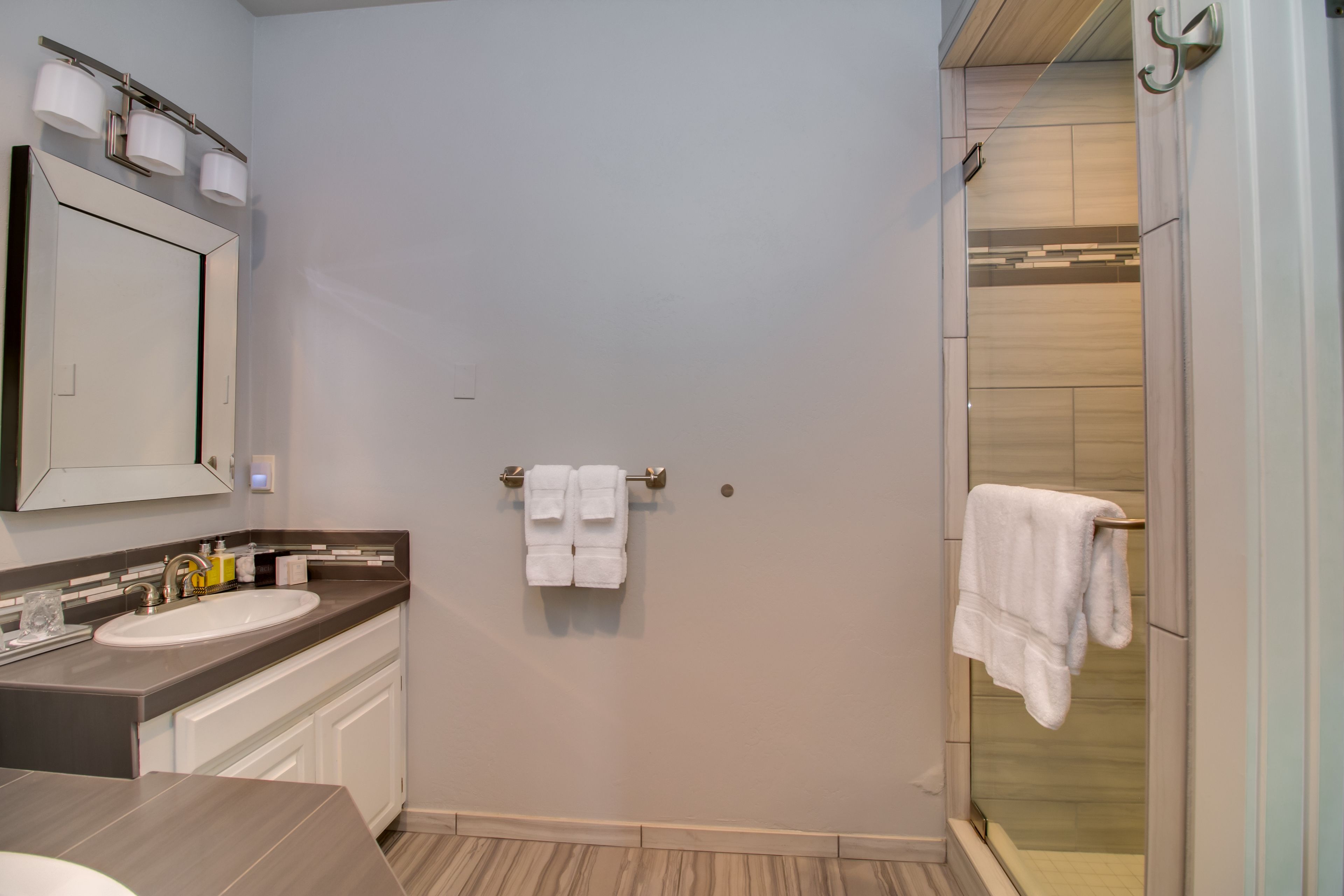 A modern bathroom with a sink, mirror, and towel rack.