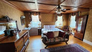 A traditional room with a bed, dresser, vanity, and a ceiling fan.