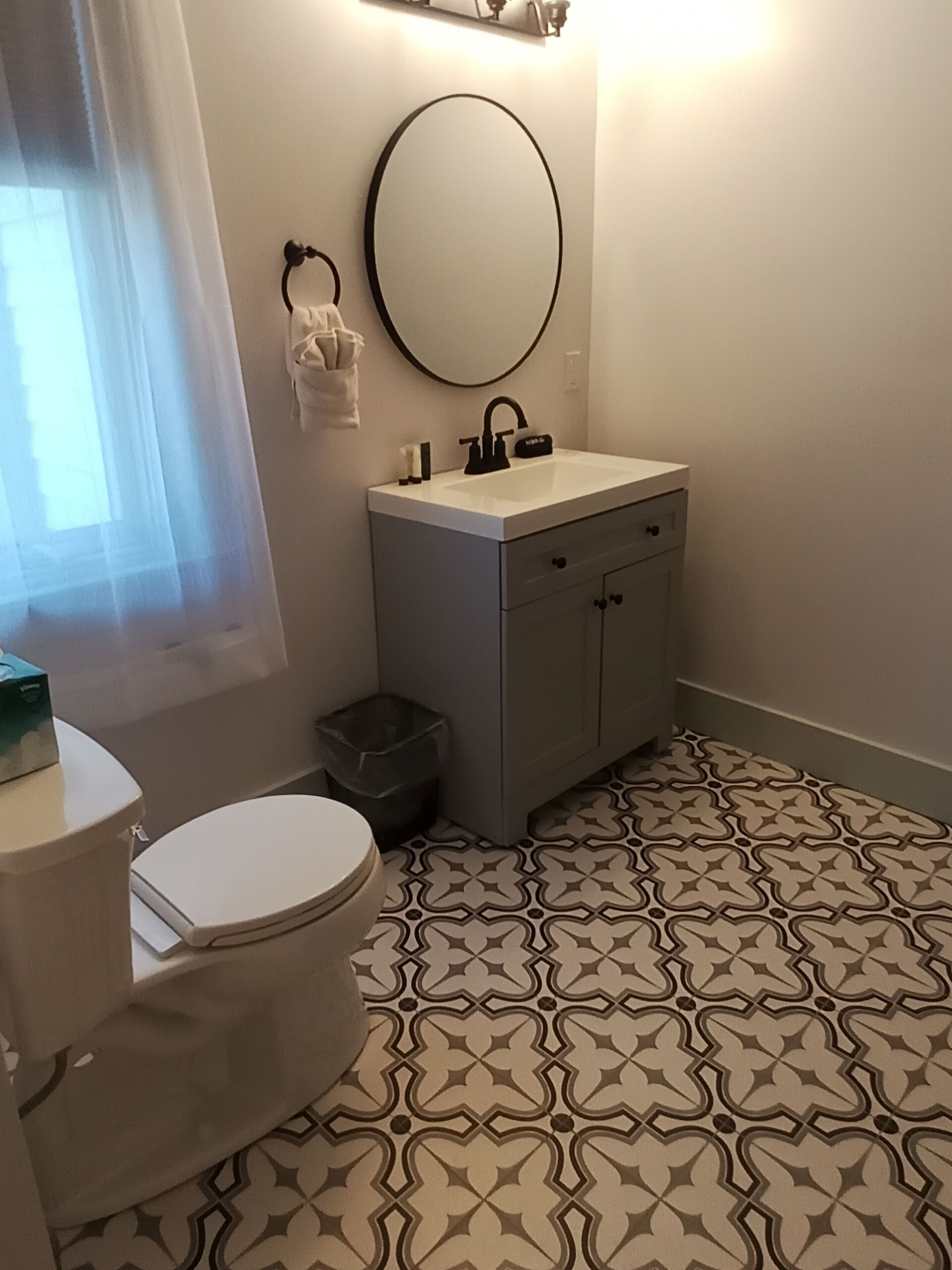 A bathroom with a toilet, sink, and mirror.