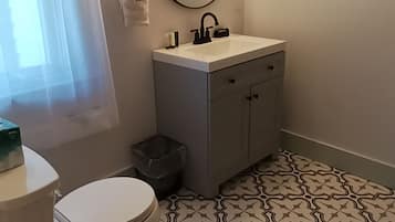 A bathroom with a toilet, sink, and mirror.