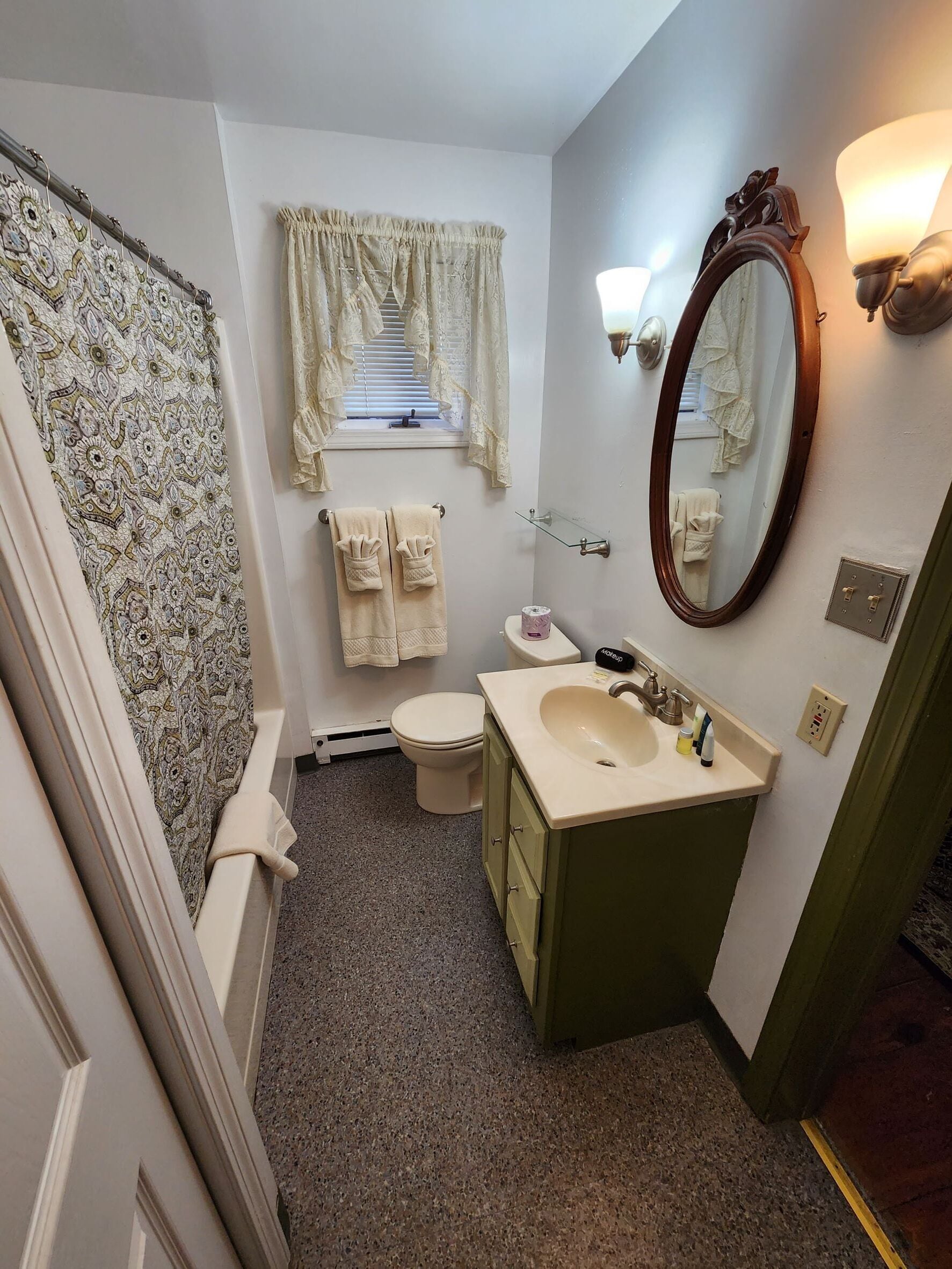 A compact bathroom with a toilet, sink, and mirror.