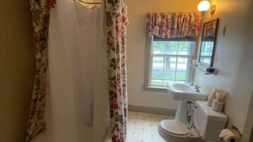Baño con ducha, inodoro, lavamanos y ventana con vistas.
