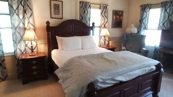 A neatly arranged bedroom with a large bed, two bedside tables with lamps, a dresser, and a chair.