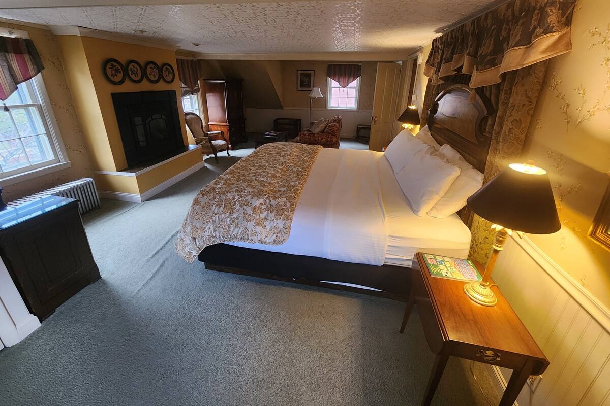 Une chambre à coucher comprenant un lit, un bureau, une chaise, un radiateur et une cheminée.
