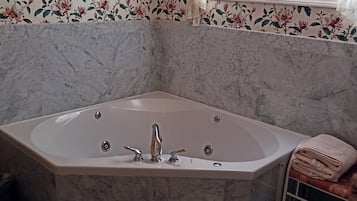 Un baño con una bañera independiente, baldosas de mármol y papel tapiz floral.