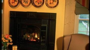 A living room with a fireplace, a brown armchair, and a vase with flowers.