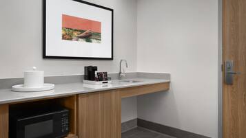 A modern kitchen with a microwave, coffee maker, and sink.