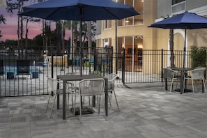 An outdoor patio area with tables and chairs, a fence, and umbrellas. - Hampton Inn & Suites Lake City (Lake City)